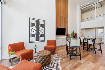 A living room with orange chairs and a zebra rug.